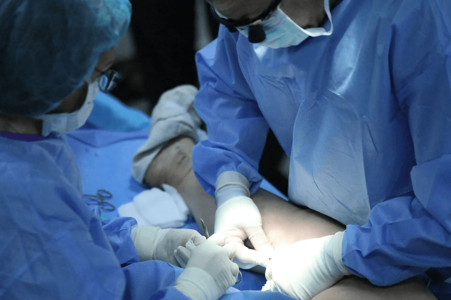 Vein specialists performing a procedure on a patient's leg in a clinical treatment setting